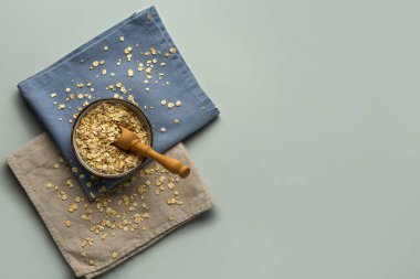 Çiğ yulaf ezmeli kase ve gri arka planda peçeteler.