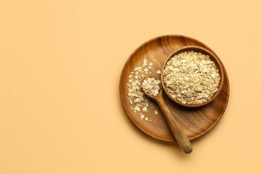 Ahşap kase çiğ yulaf ezmesi ve kaşık rengi arka planda.