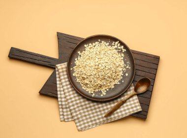 Ahşap tahta tahta, arka planda çiğ yulaf ezmesi ve kaşık.