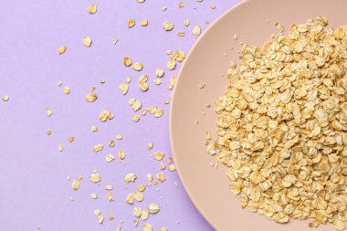 Leylak arka planında çiğ yulaf ezmeli tabak, yakın plan.