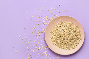 Leylak arka planında çiğ yulaf ezmeli tabak.