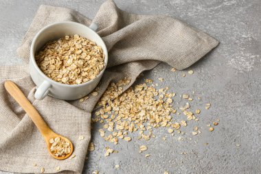 Arkaplanda çiğ yulaf ezmesi ve kaşık olan kase.