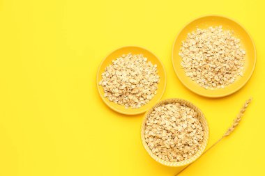 Sarı arka planda çiğ yulaf ezmesi tabakları