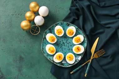 Yeşil arka planda yumurtalı tabak ve tutucu. Paskalya kutlaması