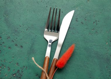 Yeşil arka planda çiçek dekoru olan çatal ve bıçak.