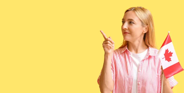 Mulher Madura Com Bandeira Canadense Apontando Para Algo Fundo Amarelo — Fotografia de Stock