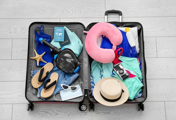 Kadın plaj aksesuarları, bağışık pasaport ve beyaz ahşap arka planda şnorkelli maske.