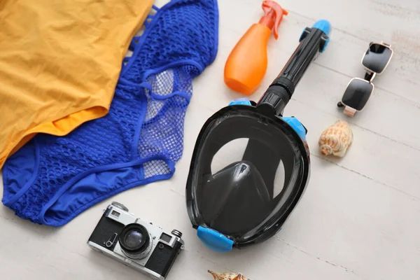Dalış maskeli kadın plaj aksesuarları ve beyaz ahşap arka planda fotoğraf makinesi.