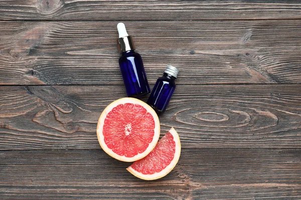 Kesilmiş greyfurt ve ahşap arka planda gerekli yağ şişeleriyle kompozisyon
