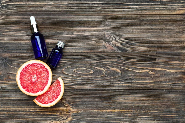 Kesilmiş greyfurt ve ahşap arka planda gerekli yağ şişeleriyle kompozisyon