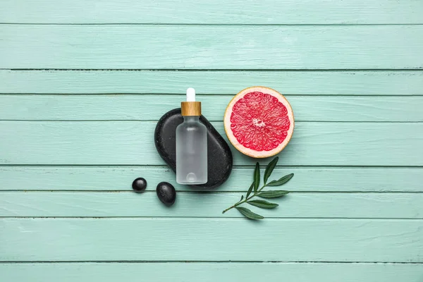Renkli ahşap arka planda greyfurt ve gerekli yağın yarısıyla kompozisyon