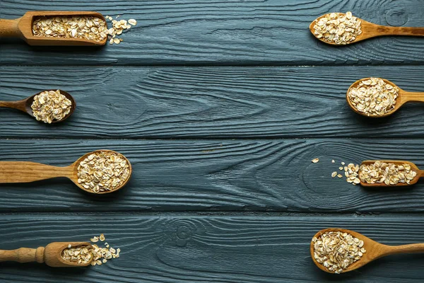 Koyu ahşap arka planda çiğ yulaf ezmeli kaşıklar ve kepçeler.