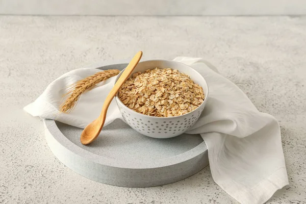 Hafif arka planda bir kase çiğ yulaf ezmesi ve kaşık