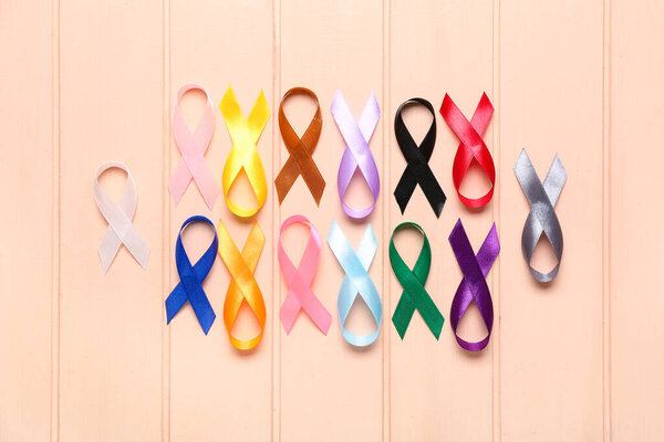 Set of colorful awareness ribbons on color wooden background. World Cancer Day