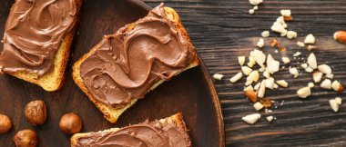 Tahta arka planda taze ekmek ve fındık ezmeli çikolata.