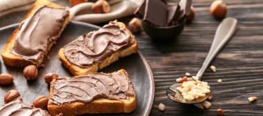 Tahta arka planda taze ekmek ve fındık ezmeli çikolata.