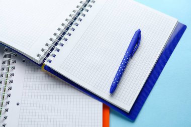 Açık mavi arkaplanda defterler ve kalem, yakın plan