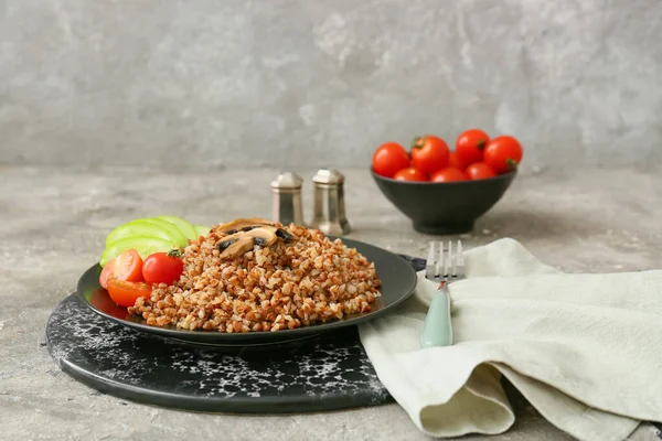 Gri masada sebzeli ve mantarlı lezzetli karabuğday lapası tabağı.