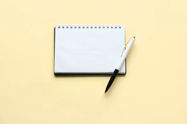 薄黄色の背景にノートとペン — ストック写真