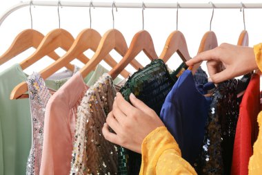 Kadın eli ve askısı farklı elbiseler, yakın plan.