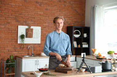 Genç adam mutfakta video dersi yaparken mantar kesiyor.