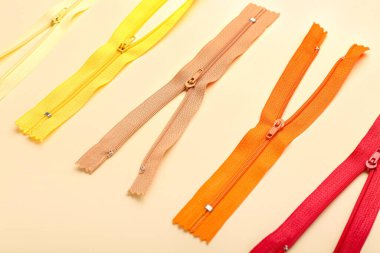 Stylish different zippers on beige background