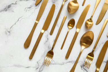 Açık mermer zemin üzerinde birçok farklı altın çatal bıçak, üst görünüm