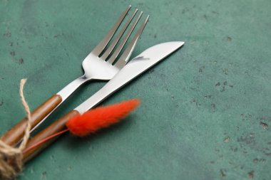 Yeşil arka planda çiçek dekoru olan çatal ve bıçak.