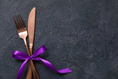 Koyu arkaplanda kurdeleli çatal ve bıçak, üst görünüm