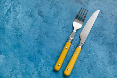 Mavi arka planda gümüş bıçak ve çatal