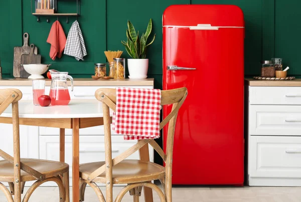 Modern mutfak, yemek masası, şık buzdolabı ve tezgahlar.