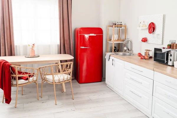 İçinde retro buzdolabı, beyaz tezgah ve yemek masası olan aydınlık mutfak.