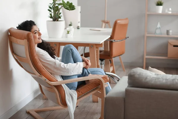 Young barefoot woman relaxing in armchair at home