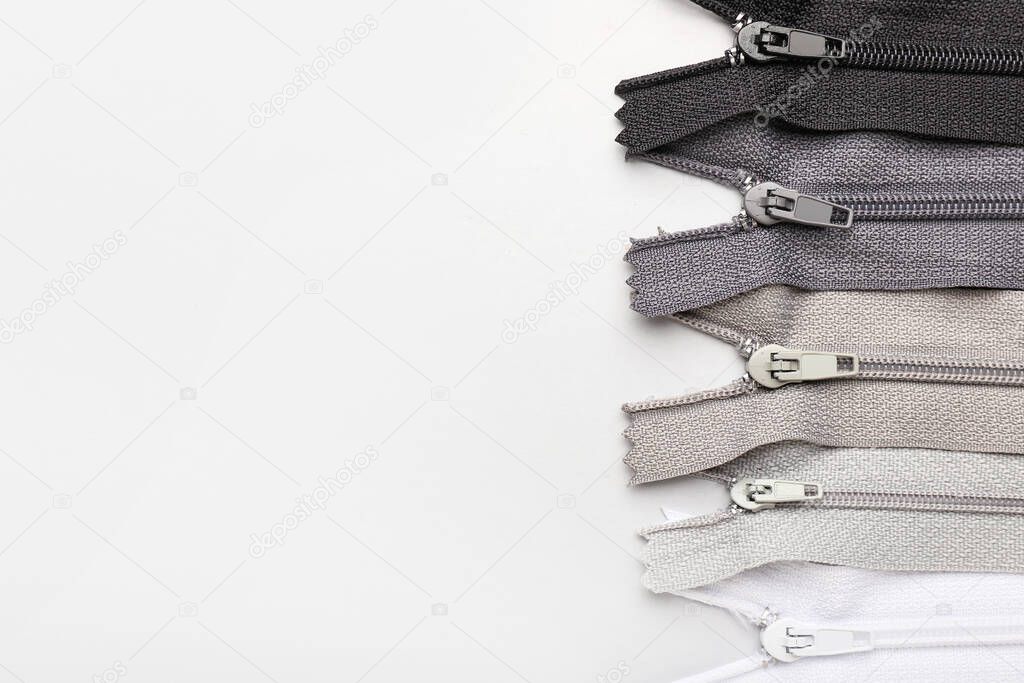 Stylish different zippers on light background