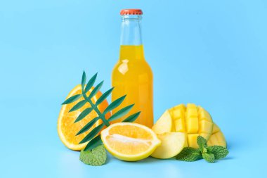 Bir şişe lezzetli soda ve mavi arka planda meyveler.