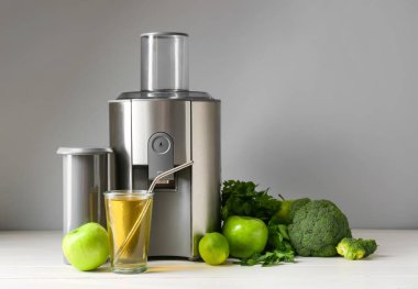 Yeni modern meyve sıkacağı ve bir bardak taze meyve suyu.