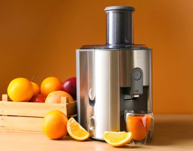 Yeni modern meyve sıkacağı ve bir bardak taze meyve suyu.