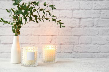 Yanan mumları ve okaliptüs dalları olan cam tutucular.