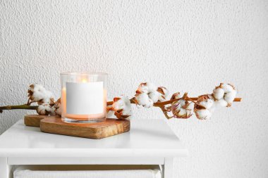 Masada yanan mum ve pamuk dalı olan tutucu.