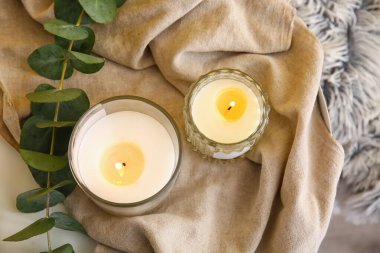 Masada yanan mumlar ve okaliptüs dalı olan tutucular, yakın plan.