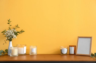 Elinde mumlar, fotoğraf çerçevesi ve çiçekler olan tutucular.