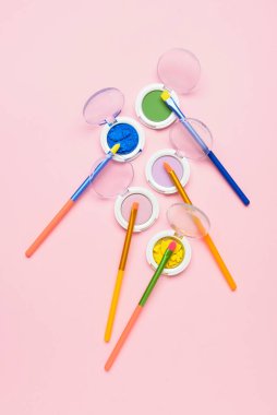 Pembe arka planda göz farı olan renkli makyaj fırçaları