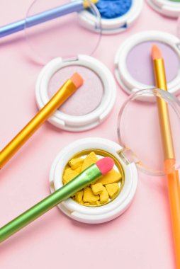 Pembe arka planda göz farı olan renkli makyaj fırçaları, yakın plan