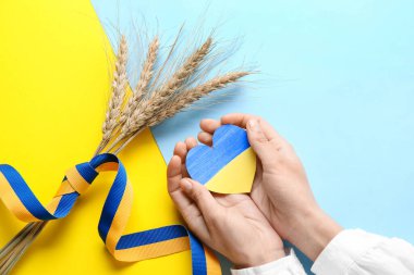 Ukrayna bayrağı, dikenler ve sarı ve mavi arka planda kurdele renginde kalbi olan eller.