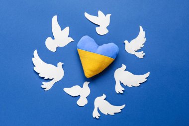Ukrayna bayrağı renginde kalp ve mavi arkaplanda barışın sembolü olarak kağıt güvercinler