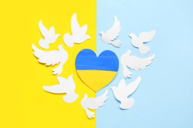 Sarı ve mavi arkaplanda barışın sembolü olarak Ukrayna bayrağı ve kağıt güvercinleri renginde kalp