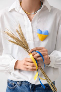 Dikenli, kurdeleli ve kalbi beyaz arka planda Ukrayna bayrağı renginde bir kadın.