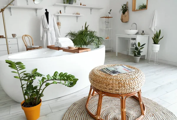 Küveti, mankeni ve çiçekleri olan hafif banyonun içi.