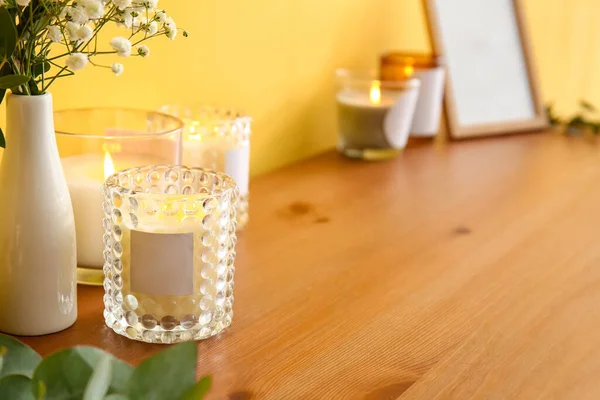 Masada yanan mumlar ve çiçekler olan tutucular, yakın plan.