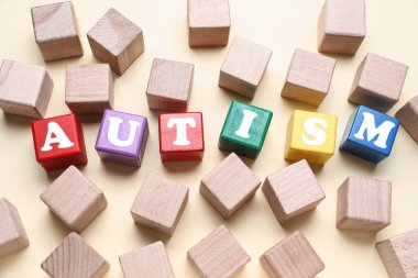 Işık arkaplanındaki küplerden oluşan kelime AUTISM